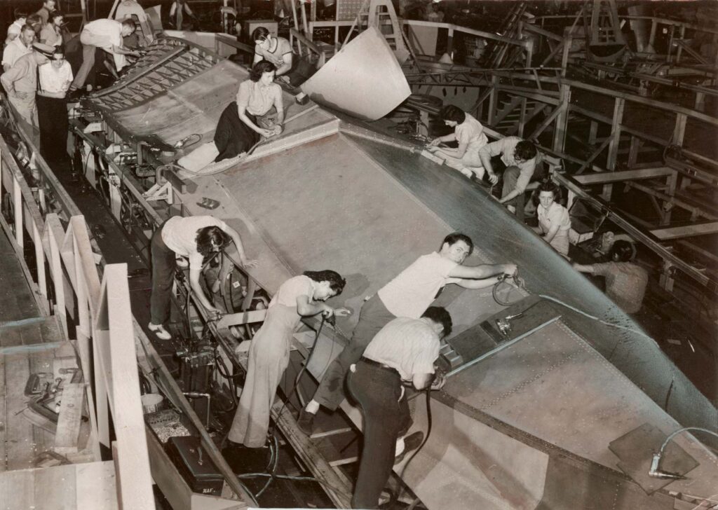 Male and female employees work on the undercarriage of an aircraft bomber at the Navy Yard, 1942. Philadelphia Record Photograph Collection, Historical Society of Pennsylvania.